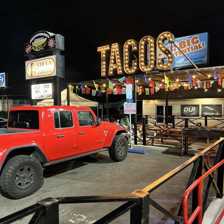 Truck parked under the Chula Tacos neon sign at night