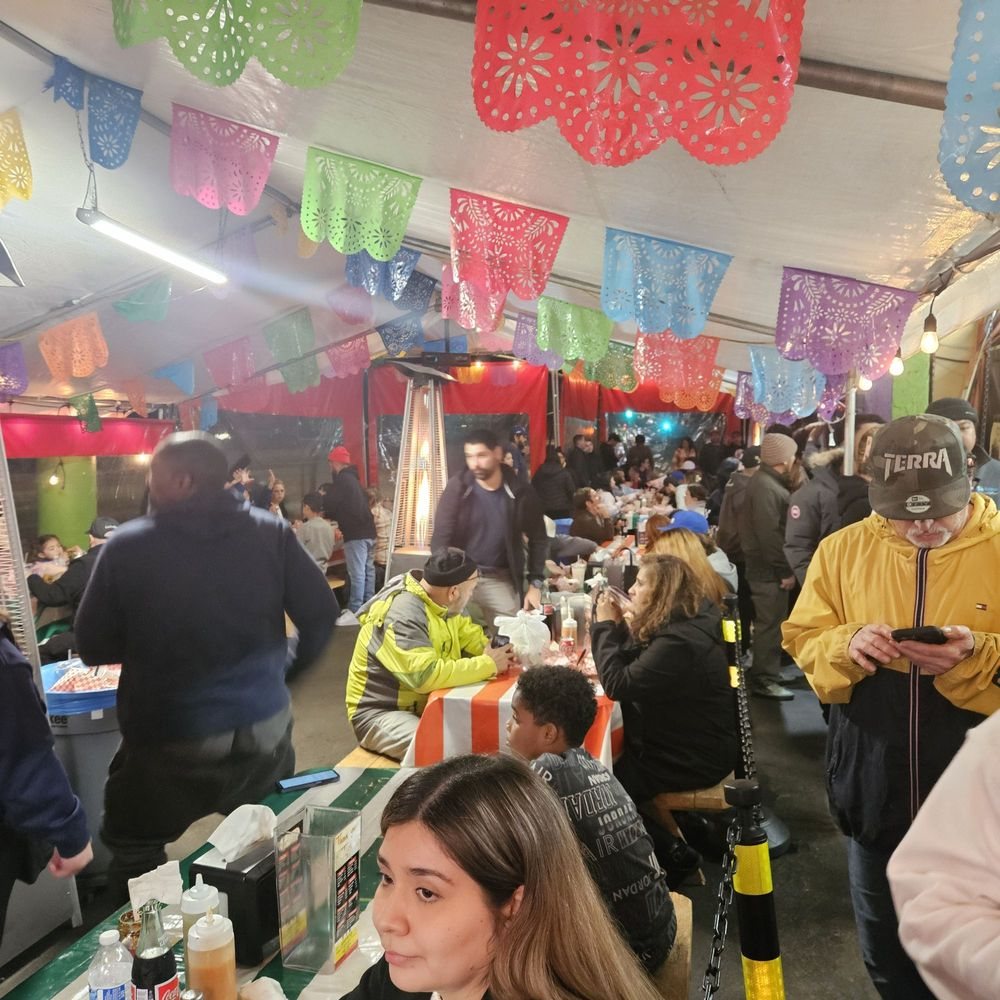 Crowd dining at Chula Tacos under papel picado at night