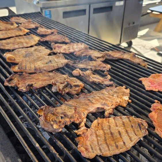 Carne asada grilling over charcoal at Chula Tacos